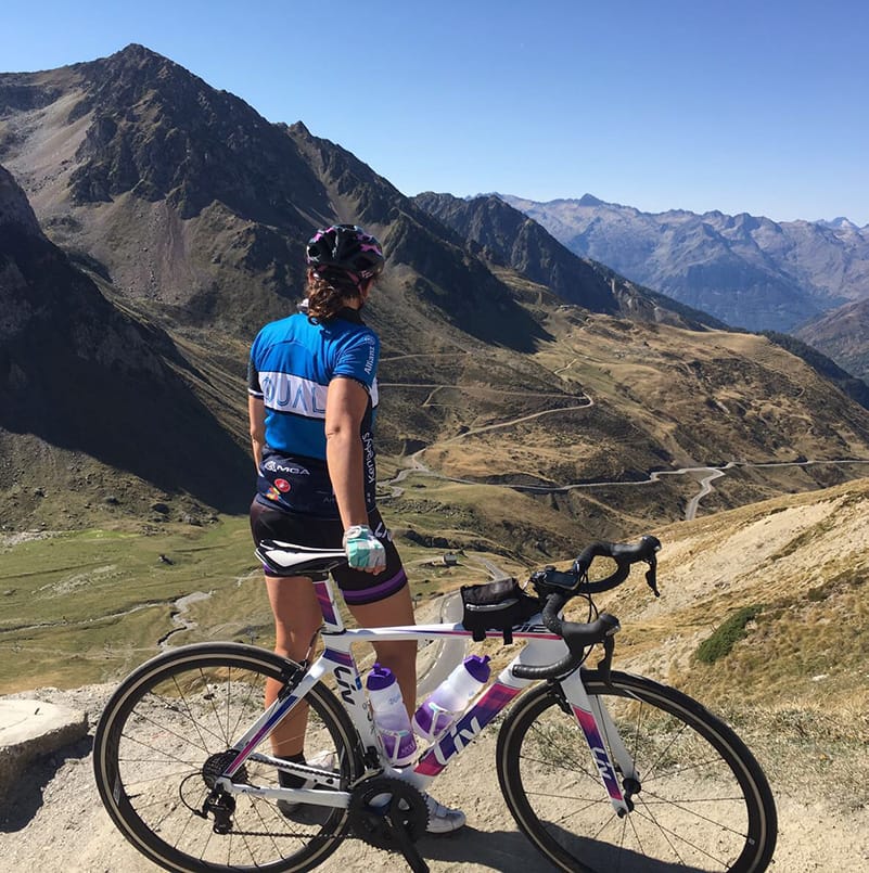 A woman standing with a mountain bike at the top of a mountain path